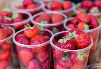 strawberries in plastic transparent glasses close-up.  lots of red ripe berries. Juicy and healthy berry