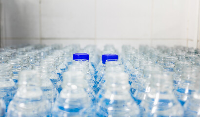 Lots of water bottles. Bottles with blue caps. Bottling plant-Water bottling line for processing and bottling drink water into bottles.