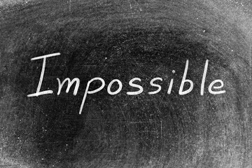 White chalk hand writing in word impossible on blackboard background