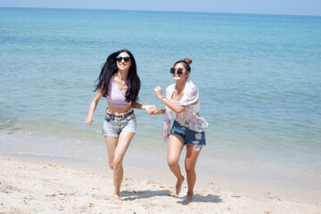 Young female tourists walking on the beach by the sea.