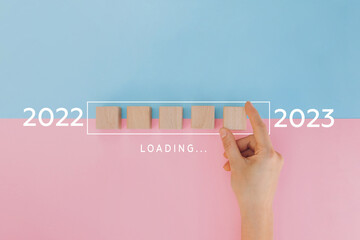 Female hand putting wooden cube for countdown to 2022. Loading year from 2022 to 2023. New year start concept
