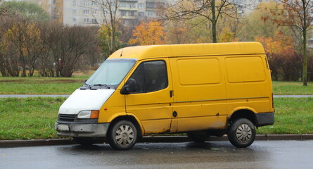 An old yellow minibus with a white hood is parked on the street, Podvoysky Street, St. Petersburg,...