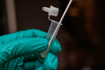 Close up on a gloved hand of a doctor or a nurse performing a covid test. Blurred background