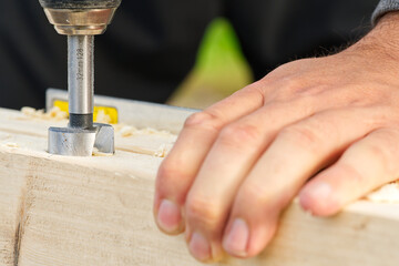 Carpenter drilling holes in the wood beam. wooden frame domestic house building. drilling a hole with a handheld drill
