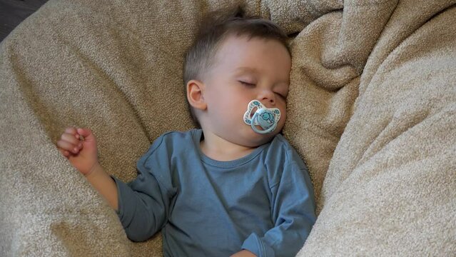 Baby boy sleeping in a beanbag chair.