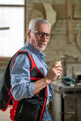 Confident mature man with a paper cup with coffee