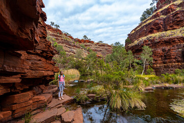 backpacker girl hiking through a canyon in karijini national park in western australia, hiking in...