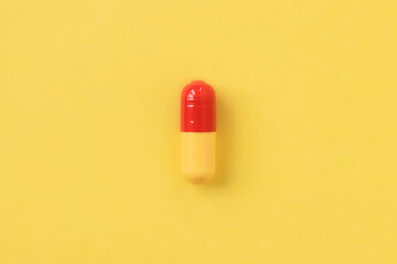 The only yellow-red capsule of the medicine on a yellow background, minimalism, macro.