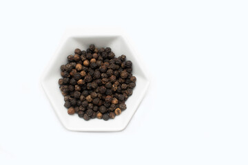 minimalist concept of natural black pepper spice on white hexagon-shaped plate