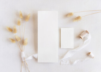 Blank cards near silk ribbons and dried hare's tail grass top view on white, boho mockup