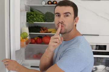 Hungry man secretly opening the fridge door 