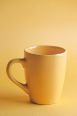 Close up of yellow coffee mug on yellow background