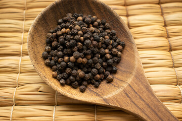 large wooden spoon with black peppercorns