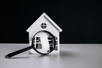 Magnifying glass and white house close-up. House selection and search, real estate concept.
