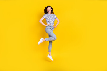 Fototapeta na wymiar Full body photo of cute young lady hands waist jumping look camera poster wear stylish striped outfit isolated on yellow color background