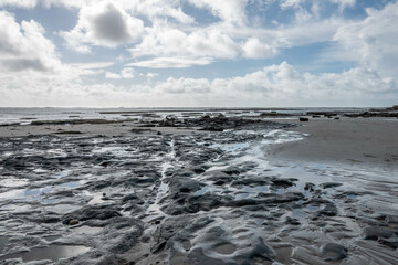 rock pools on a beautiful deserted sandy beach in Lyme Regis Dorset England Jurassic Coast with blue sky and wispy white clouds