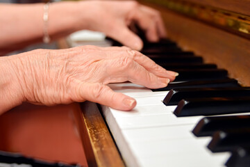 Obraz premium Close-up shot of an elderly menopausal woman playing the piano as a hobby in a nursing home 