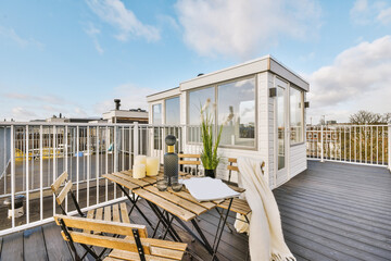 Furnished balcony of modern building with shed under blue sky