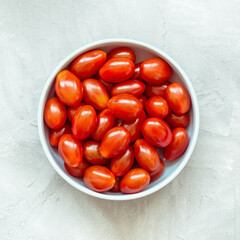 Fresh red cherry tomatoes in bowl, top view, copy space