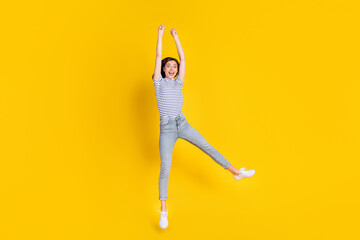 Full body photo of sporty young lady raise hands jump hang hold copyspace wear trendy striped...