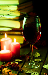A glass of steaming wine on the table next to books and candles