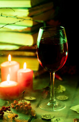 A glass of steaming wine on the table next to books and candles