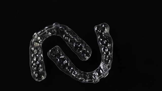 Invisible orthodontics cosmetic brackets on black background. Tooth aligners, for beautiful smile.
