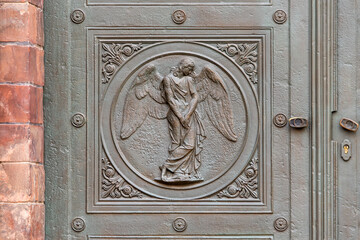 Angel carving on church doors in Berlin, Germany. Detail of the metallic panel on the temple doorway, entrance to the church.