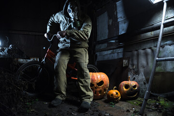 Fototapeta na wymiar a man in a gas mask with orange halloween pumpkins celebrates the holiday