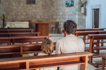 Christian dad tells his son Bible stories about Jesus sitting in kirk. Faith, religious education, modern church, father day, fatherly responsibilities, father influence on formation of son worldview