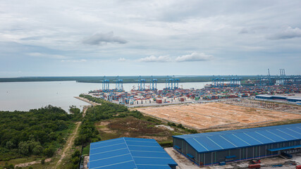 Obraz premium Klang, Malaysia - October 09, 2022: Cranes at the port Klang near Kuala Lumpur. Container crane at Klang Harbor. Aerial view on a container ship which is being loaded. Heavy Trucks at the Cargo bay