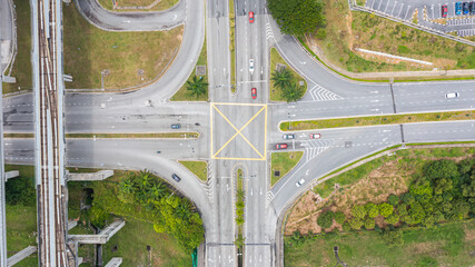 Traffic junctions, modern city. View from above to busy road junction in Malaysia. Colorful cars and trucks driving straight forward in both directions crossing the road. Aerial view of road crossing