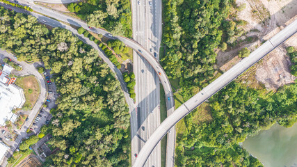 Aerial view directly above a six lane highway. Top view of asphalt road passes through the field and forest. Aerial. Sedan cars driving by the highway. Top view from drone. aerial photo autobahn road