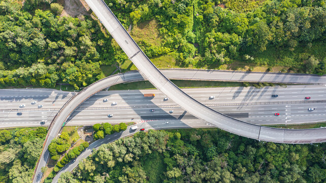 Aerial view directly above a six lane highway. Top view of asphalt road passes through the field and forest. Aerial. Sedan cars driving by the highway. Top view from drone. aerial photo autobahn road
