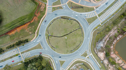 Aerial top down view of traffic roundabout on a main road. Aerial view of roundabout in the city in the summer. Aerial view of traffic infrastructure. Sedan cars moving over the asphalt. Road crossing