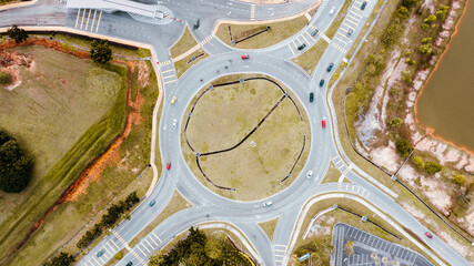 Aerial top down view of traffic roundabout on a main road. Aerial view of roundabout in the city in the summer. Aerial view of traffic infrastructure. Sedan cars moving over the asphalt. Road crossing