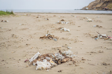 Spilled garbage on the beach. Empty used dirty plastic bottles. Environmental pollution. Ecological problem