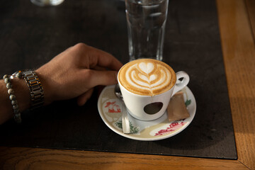 Woman hands holding cappuccino in a cafe bar
