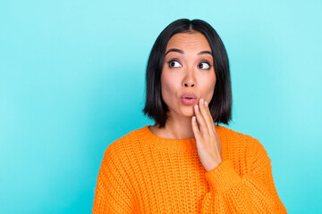 Photo of impressed girl with bob hairdo dressed orange pullover look empty space palm on cheek isolated on turquoise color background