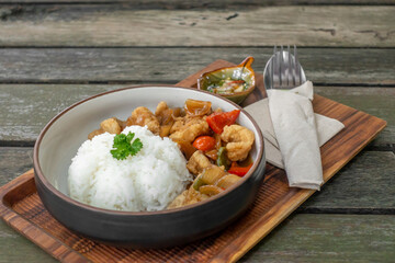 The dish of fried pork or fish with whtie jasmine rice topped by cyrantro with spoon and fork set in restaurant.  - Powered by Adobe