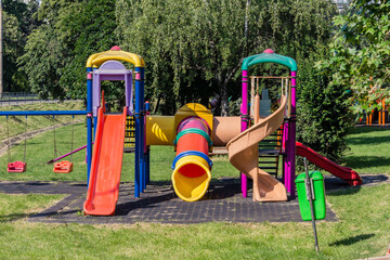 Colorful playground equipment made of plastic surrounded by green trees
