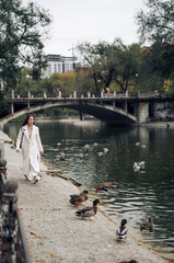 Young pretty woman walks in park near lake with ducks.
