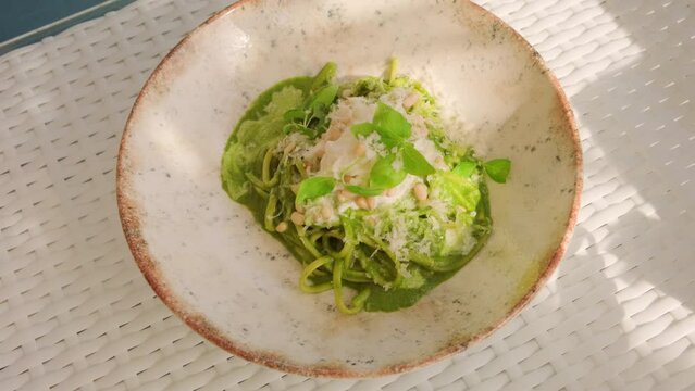 Serving pasta with pesto and stracciatella cheese in restaurant. Italian cuisine dish.