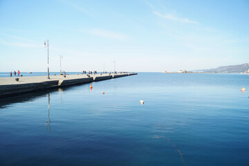 Molo presso la banchina del porto doi Trieste con cielo azzurro e mare calmo colore blu intenso - obrazy, fototapety, plakaty