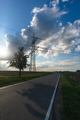 Electricity pylon for transmission and current transfer of high voltage through natural landscapes in front of cloudy sky