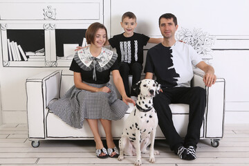 Happy family: mom, dad, son, dalmatian dog together at home. Interior in black and white colors....