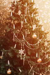 christmas and new year time. christmas tree decorated in vintage retro style with balloons, snowflakes, candles and garlands of beads. green fir or spruce. winter holiday season at home. flare