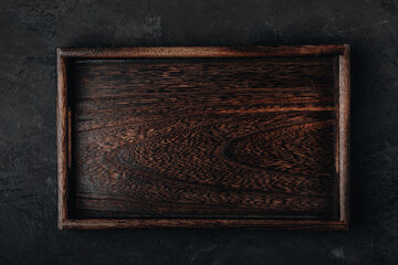 Wooden tray. Wooden tray, plate, cutting board on dark stone concrete background, top view.