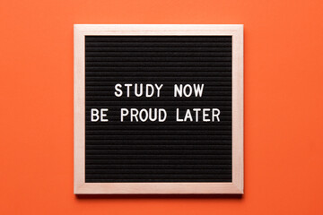 Motivational quote on black letter board on orange background. Study now be proud later....