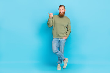 Full body photo of attractive young man stand point empty space shopping dressed stylish khaki look isolated on aquamarine color background